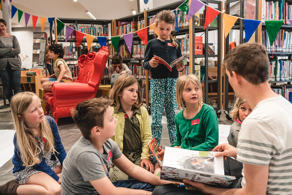 kinderen luisteren naar een jeugdauteur in de bib