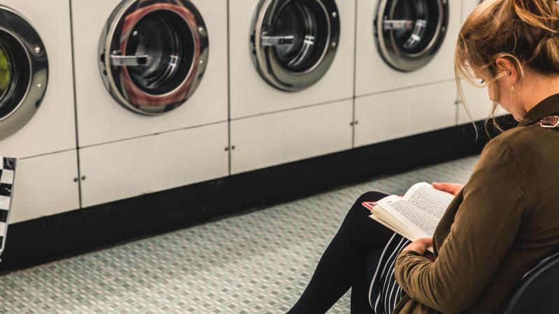 een vrouw leest een boek in een wassalon.