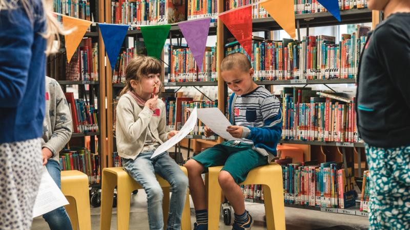Kinderen nemen deel aan een boekenzoektocht in de bibliotheek