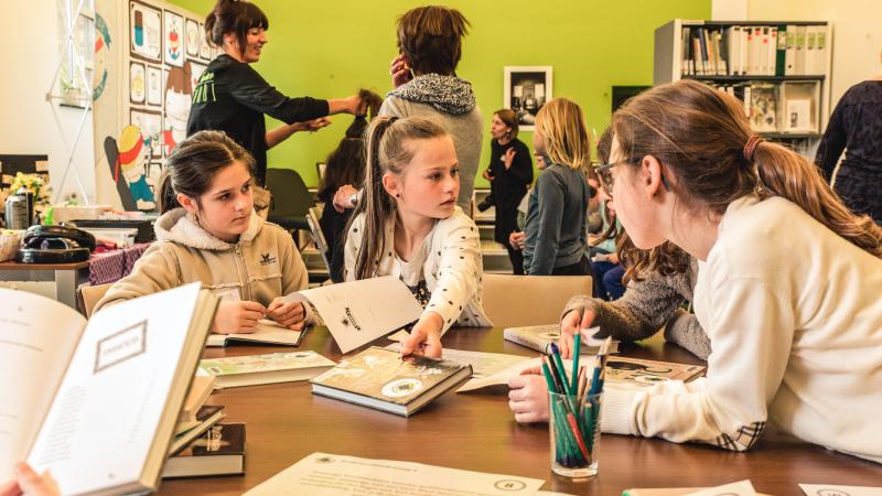 Kinderen werken rond boeken in de klas