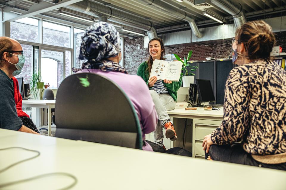 een lesgeefster leest voor aan volwassenen in het volwassenonderwijs