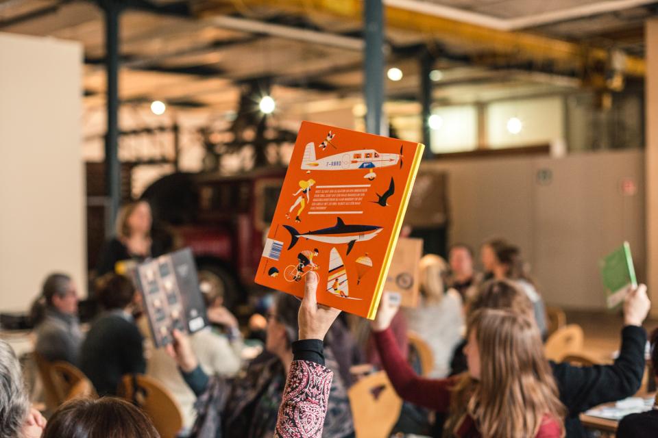 tijdens een workshop steekt een deelnemer een non-fictie boek in de lucht