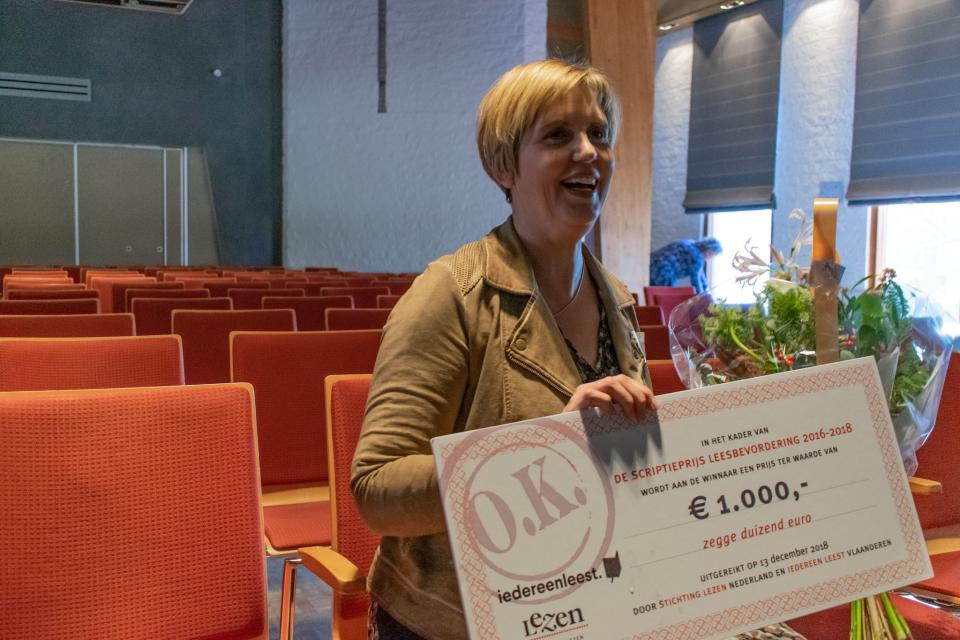 de vorige winnaar van de scriptieprijs leesbevordering houdt een cheque van €1000 in haar handen