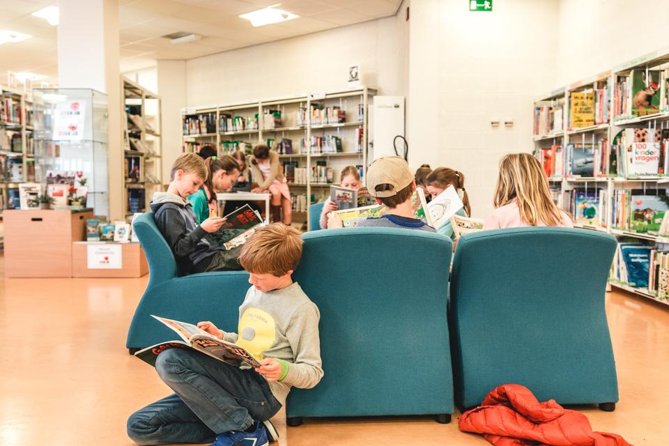 kinderen lezen al zittend strips in de bibliotheek
